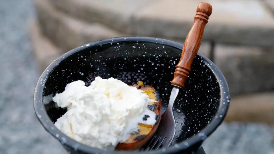 Grilled fresh peaches with blackberries warmed in a cast iron skillet topped with freshly made whipped cream and honey on Tuesday, July 25, 2023 at Bourbon Barrel Cottages in Lawrenceburg, Ky.