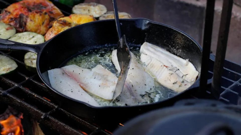 Tony Miller flips the pan seared tilapia he is cooking on Tuesday, July 25, 2023 at Bourbon Barrel Cottages in Lawrenceburg, Ky.