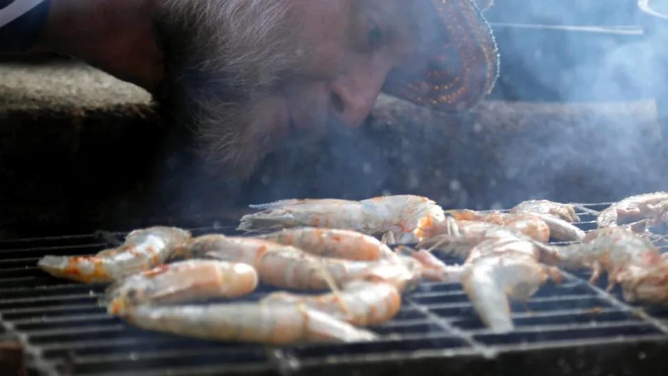 Tony Miller blows on the fire beneath the prawns he is grilling Tuesday, July 25, 2023 at Bourbon Barrel Cottages in Lawrenceburg, Ky.